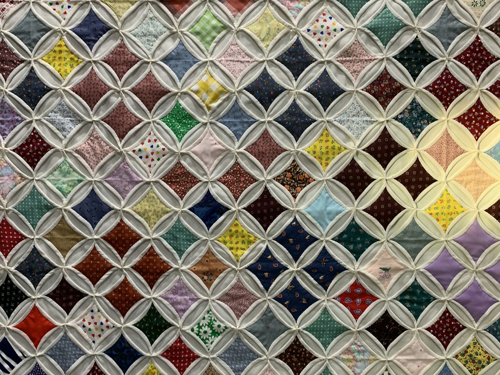 Colourful cathedral-window quilt with floral cotton panels